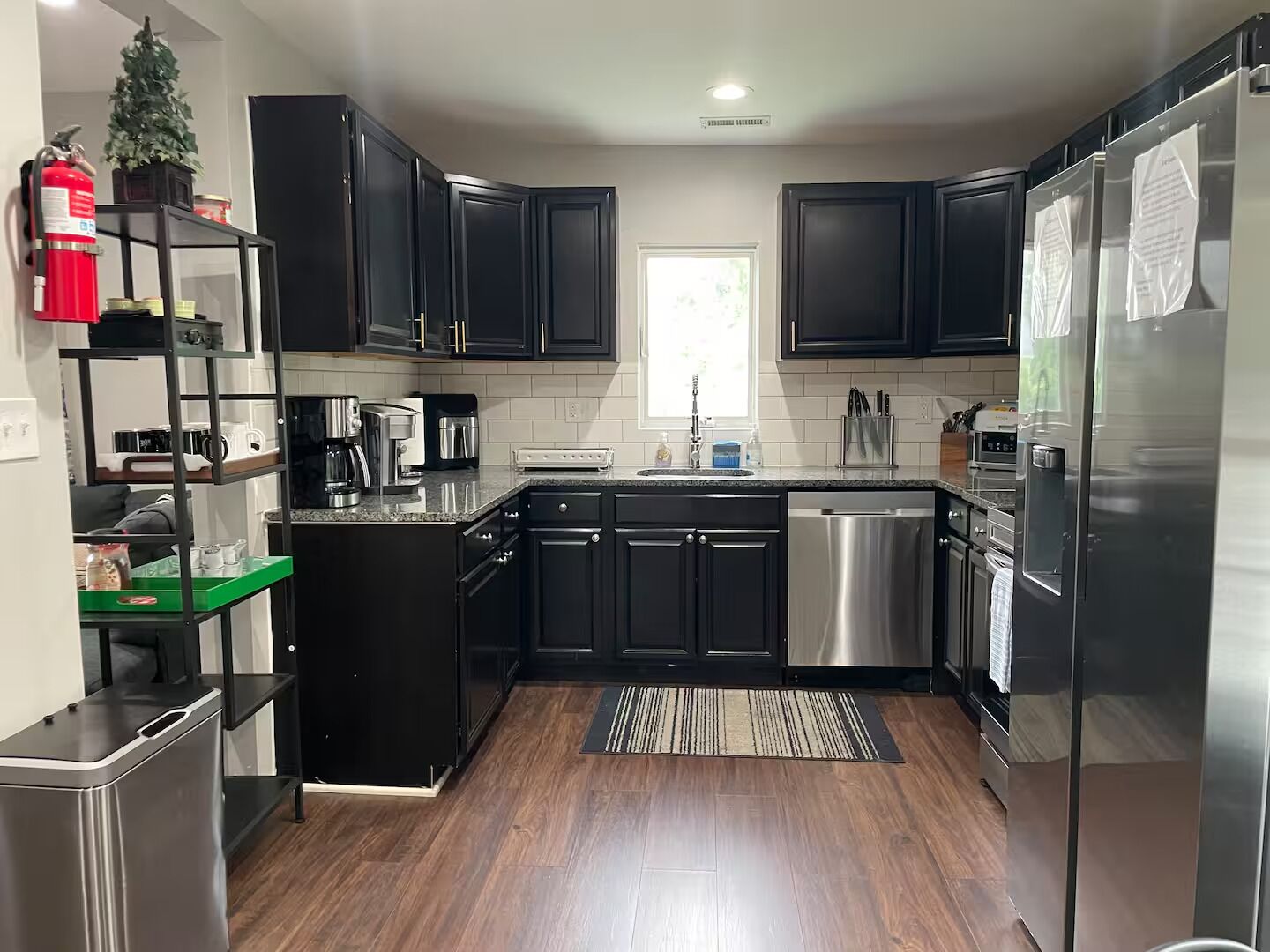 A modern kitchen with black cabinets, stainless steel appliances, and a small island with a coffee maker.