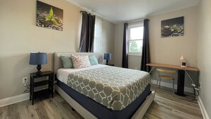 Ett hotellrum med en säng, sängbord, ett skrivbord och ett fönster.