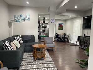 A living room with a sofa, a coffee table, and a dining area with chairs and a table. - 4-bedroom house in tranquil Baltimore Highlands with AC (Baltimore Highlands)