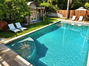 A rectangular swimming pool with clear blue water, surrounded by a wooden deck and a grassy area with lounge chairs. - Rincon Valley Poolside Wine Country Retreat (Santa Rosa)