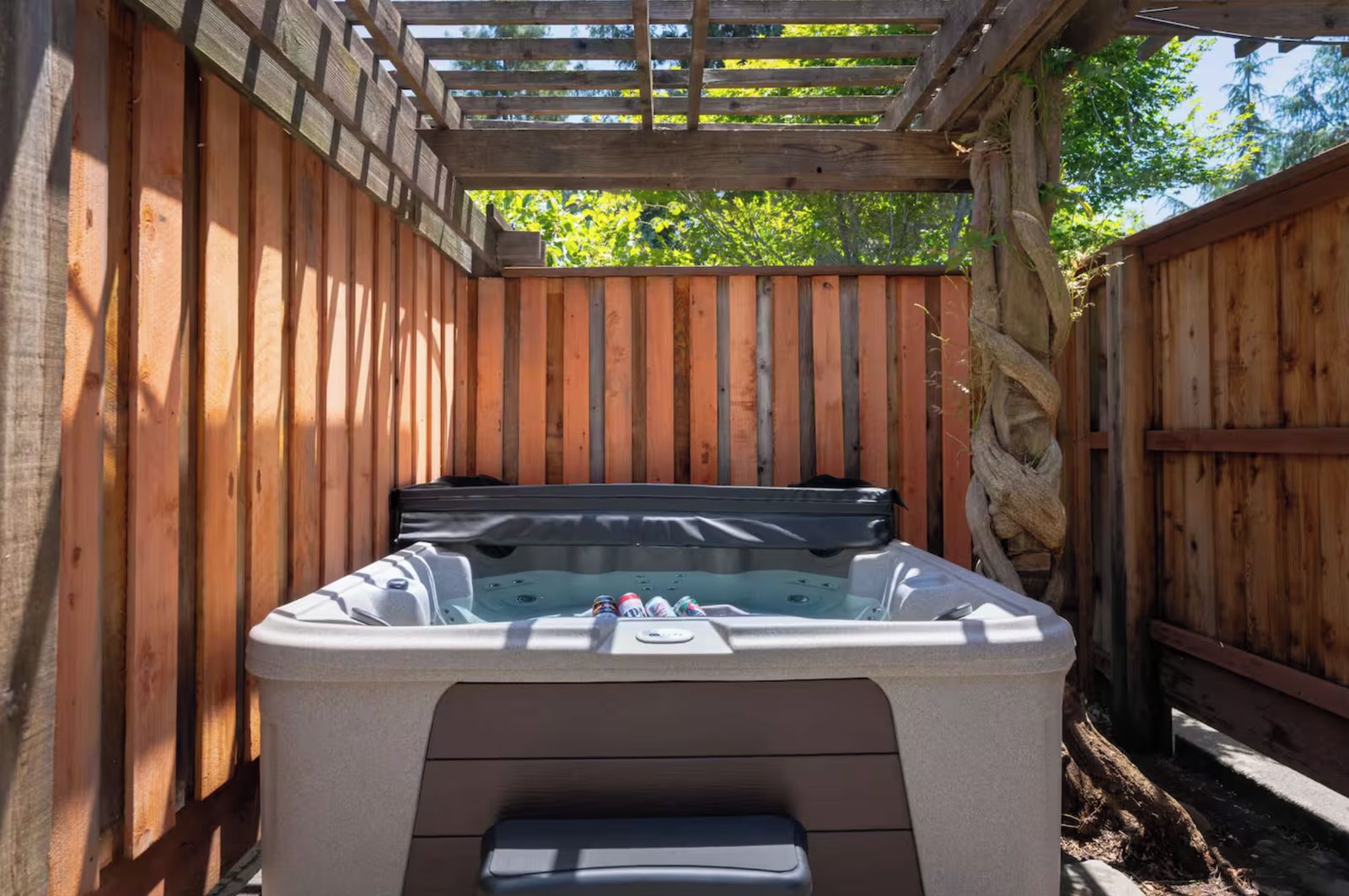 A hot tub in a wooden outdoor setting with a pergola overhead.