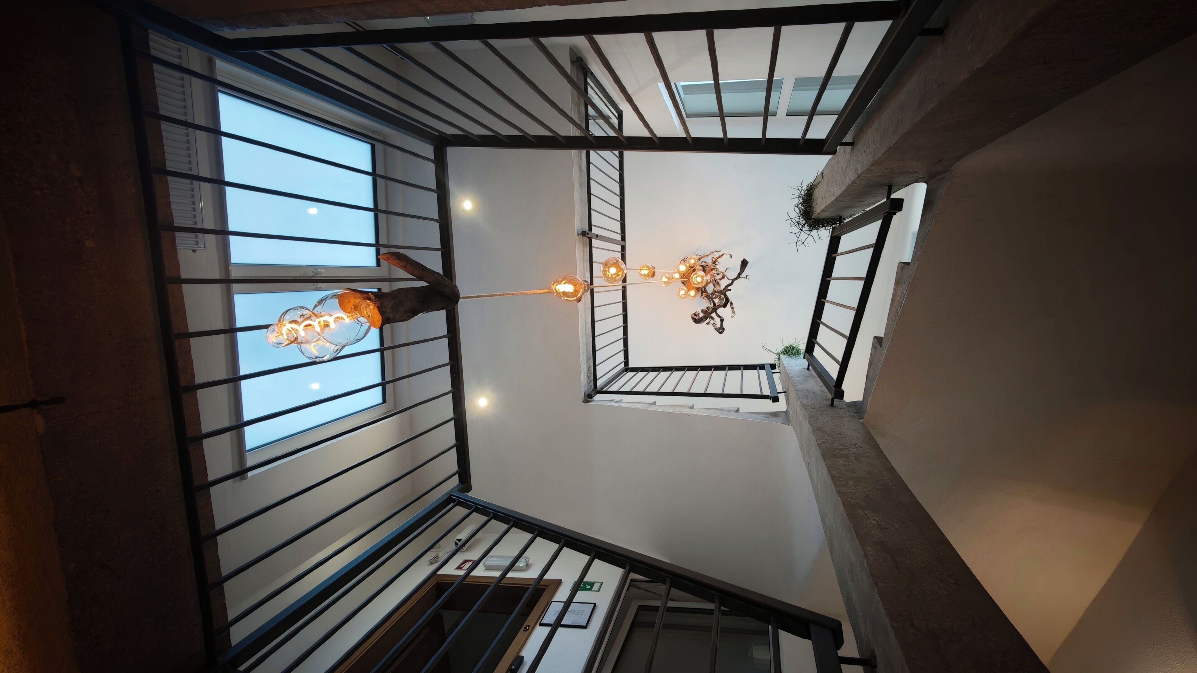 A multi-level interior with a staircase, railings, and a hanging light fixture.