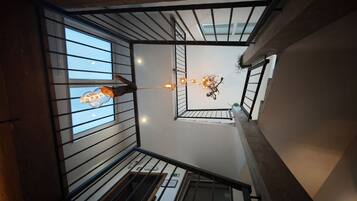 A multi-level interior with a staircase, railings, and a hanging light fixture.