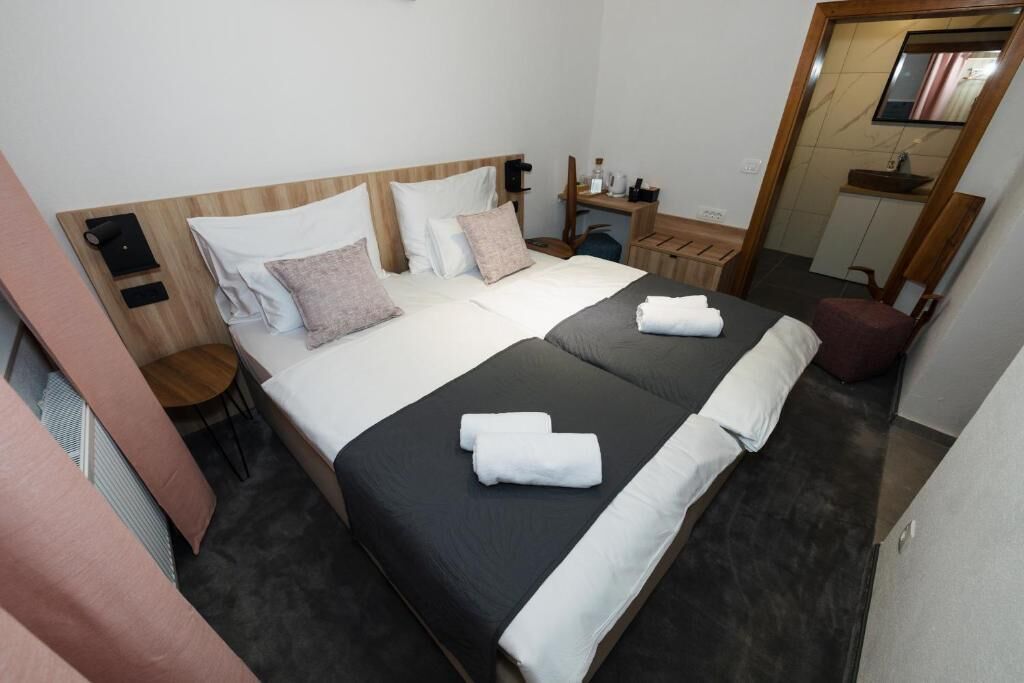 A hotel room with a bed, bedside table, and a mirror.