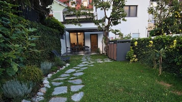 A stone pathway leading to a modern house with a visible entrance and a small patio area.