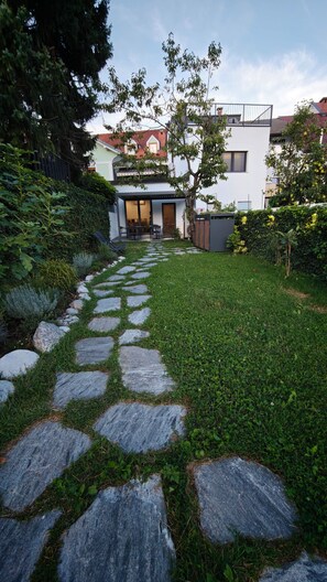 A stone pathway leading to a modern house with a visible entrance and a small patio area. - Huch House Hotel and apartments (Kranj)