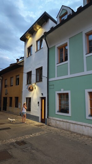 A building with a sign indicating a restaurant or cafe, a dog on a leash, and a person standing nearby. - Huch House Hotel and apartments (Kranj)