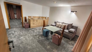 Un espacio habitable moderno y funcional, con kitchenette, sofá, mesa de comedor y una silla.