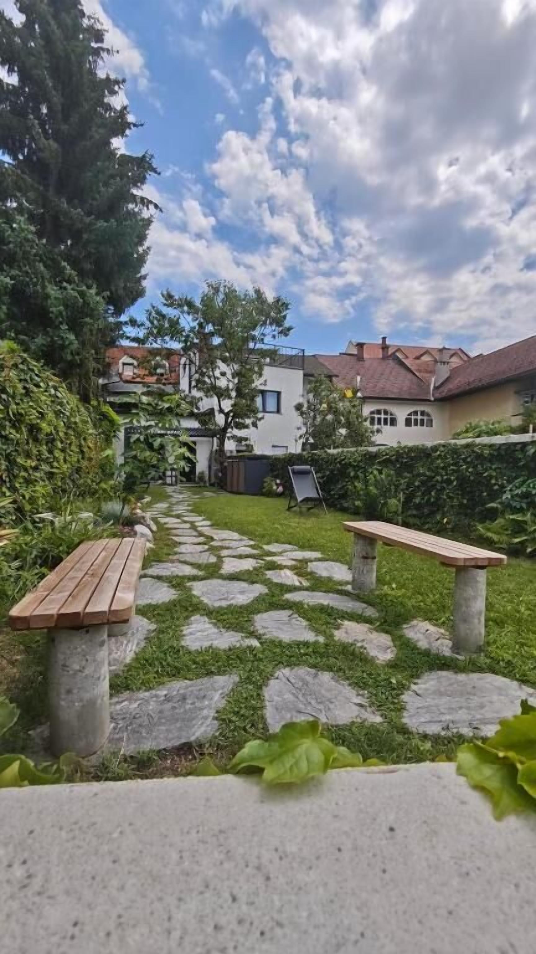 A garden pathway with stone slabs and wooden benches.