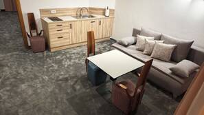 Espaço compacto com cozinha compacta, sofá, mesa de centro e uma cadeira.