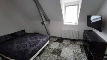 Une chambre à coucher avec un lit, une fenêtre, un radiateur et un téléviseur.
