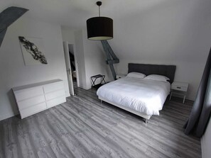 Een moderne slaapkamer met een bed, nachtkastjes, een kaptafel en een hanglamp.