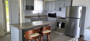 Una cucina moderna con piani in granito, elettrodomestici in acciaio inossidabile e sgabelli da bar in legno.