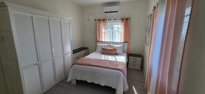A bedroom with a bed, a wardrobe, a nightstand, and a window with curtains. - Seaview property near Ocho Rios and Ian Fleming airport (Salt Gut)