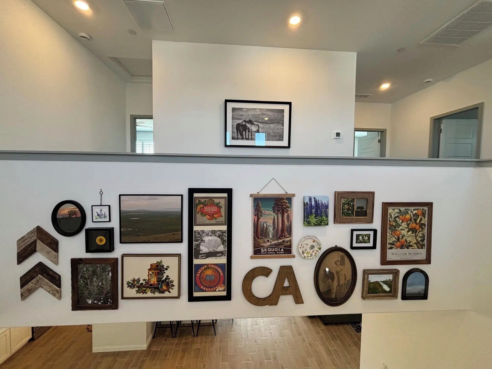 A wall with various framed pictures and a large 'CA' sign.