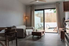 A modern living room with a sofa, a coffee table, and a dining table. There is a sliding glass door leading to an outdoor area with a pool. - House in the heart of Andalusia with private pool (Luque)