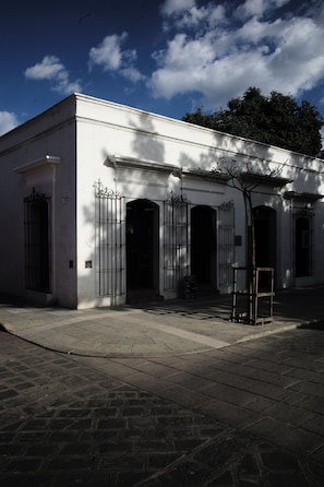 A building with a white facade, multiple doors with metal gates, and a paved entrance area. - A unique spot in Oaxaca's Historic District. Parks, restaurants, and museums within walking distance. (Oaxaca de Juárez)