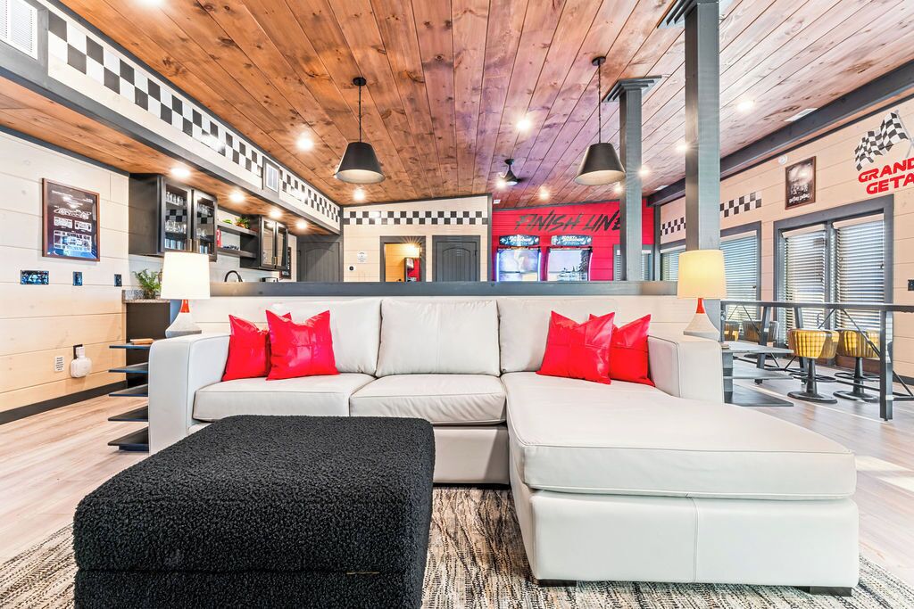 Eine moderne Hotellobby mit einem weißen Sofa, roten Kissen, einem schwarzen Hocker und einer Holzzielung. Die Wand ist mit einem Schachbrettmuster versehen.