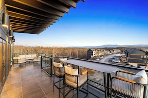 A balcony with a table and chairs, offering a view of a residential area and a road.