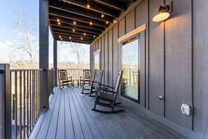 Eine überdachte Holzterrasse mit Schaukelstühlen und Lichterketten.