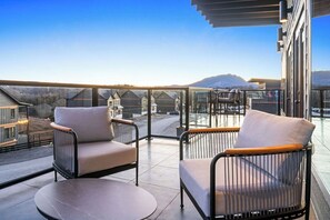 Un balcon avec deux chaises et une table, donnant sur un paysage montagneux.