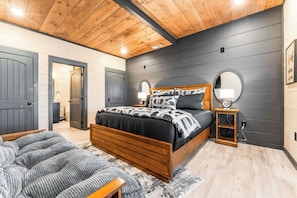 A bedroom with a wooden bed, a bedside table, a mirror, and a rug.