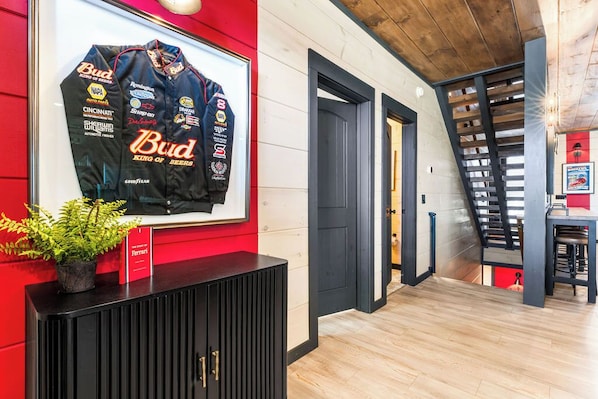 A hotel lobby with a framed racing jersey on the wall, a staircase, and a black console with a potted plant.
