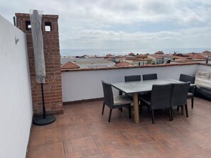 Une terrasse avec une table et des chaises, donnant sur une zone côtière avec des bâtiments.