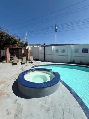 A swimming pool with a hot tub, lounge chairs, and a pergola. - Serene 2-bedroom condo in Rosarito perfect for relaxing getaways (Rosarito)
