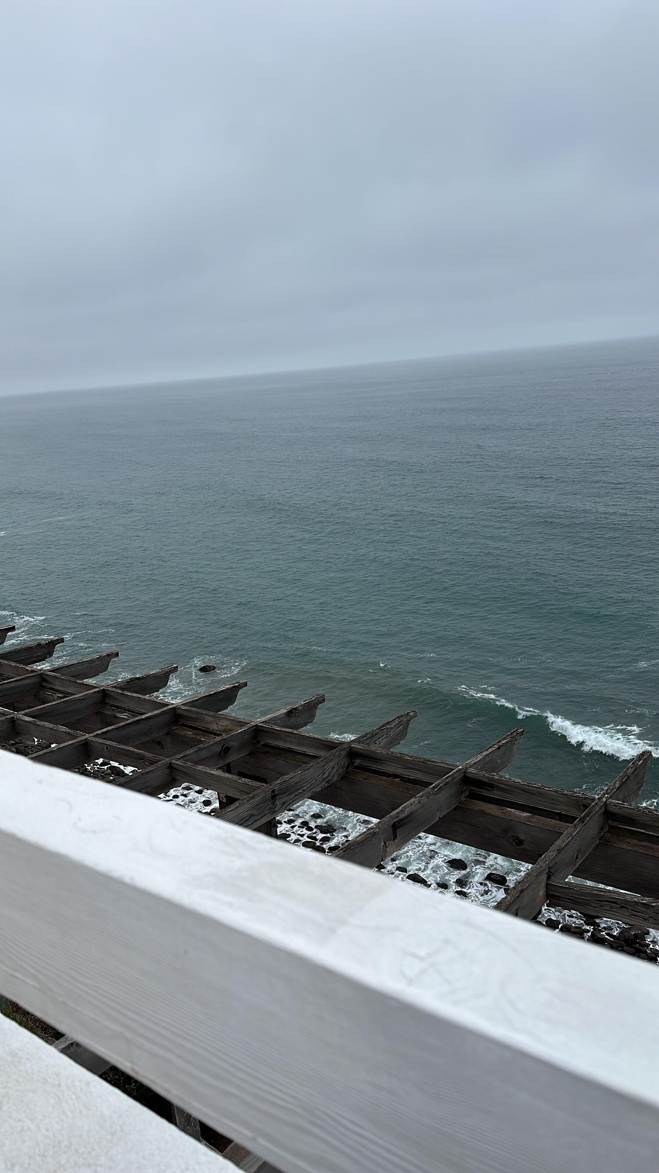 Vista del océano desde una terraza de madera con barandilla.