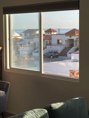 A room with a large window overlooking a residential area with houses and a clear sky. - Serene 2-bedroom condo in Rosarito perfect for relaxing getaways (Rosarito)