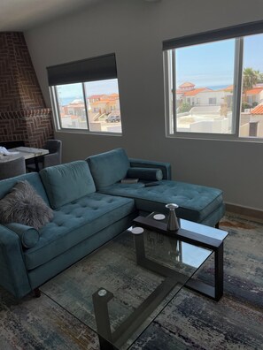 A modern living room with a sectional sofa, a glass coffee table, and a fireplace. - Serene 2-bedroom condo in Rosarito perfect for relaxing getaways (Rosarito)