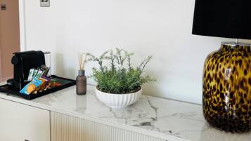 Een kamer met een witte kast, een koffieapparaat, een plant, een spel en een lamp.
