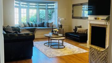 A living room with a fireplace, a television, and a large window.