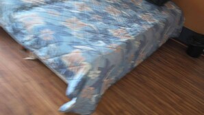 Una cama con una colcha estampada con motivos florales, un cabecero de madera y dos almohadas.