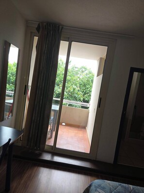 A room with a sliding glass door leading to a balcony with a view of greenery. - Cozy 1-bedroom apartment in beautiful Fleury with AC 50m from the beach (Fleury)