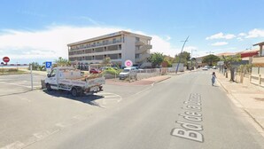 Una calle con un camión blanco estacionado al costado, un paso de cebra y un edificio con balcones.