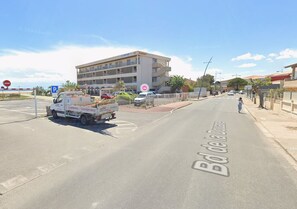 A street with a white truck parked on the side, a pedestrian crossing, and a building with balconies. - Cozy 1-bedroom apartment in beautiful Fleury with AC 50m from the beach (Fleury)