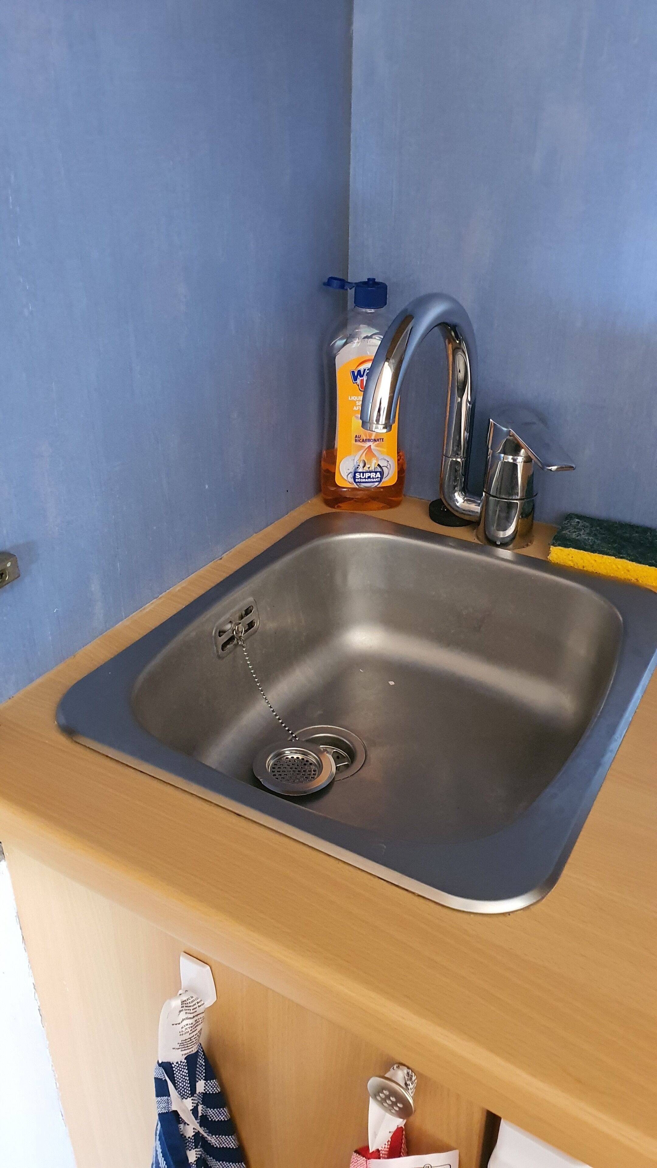 A stainless steel sink with a faucet, a soap dispenser, and a sponge.