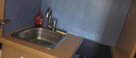 A compact kitchenette with a sink, a small stove, and a refrigerator.