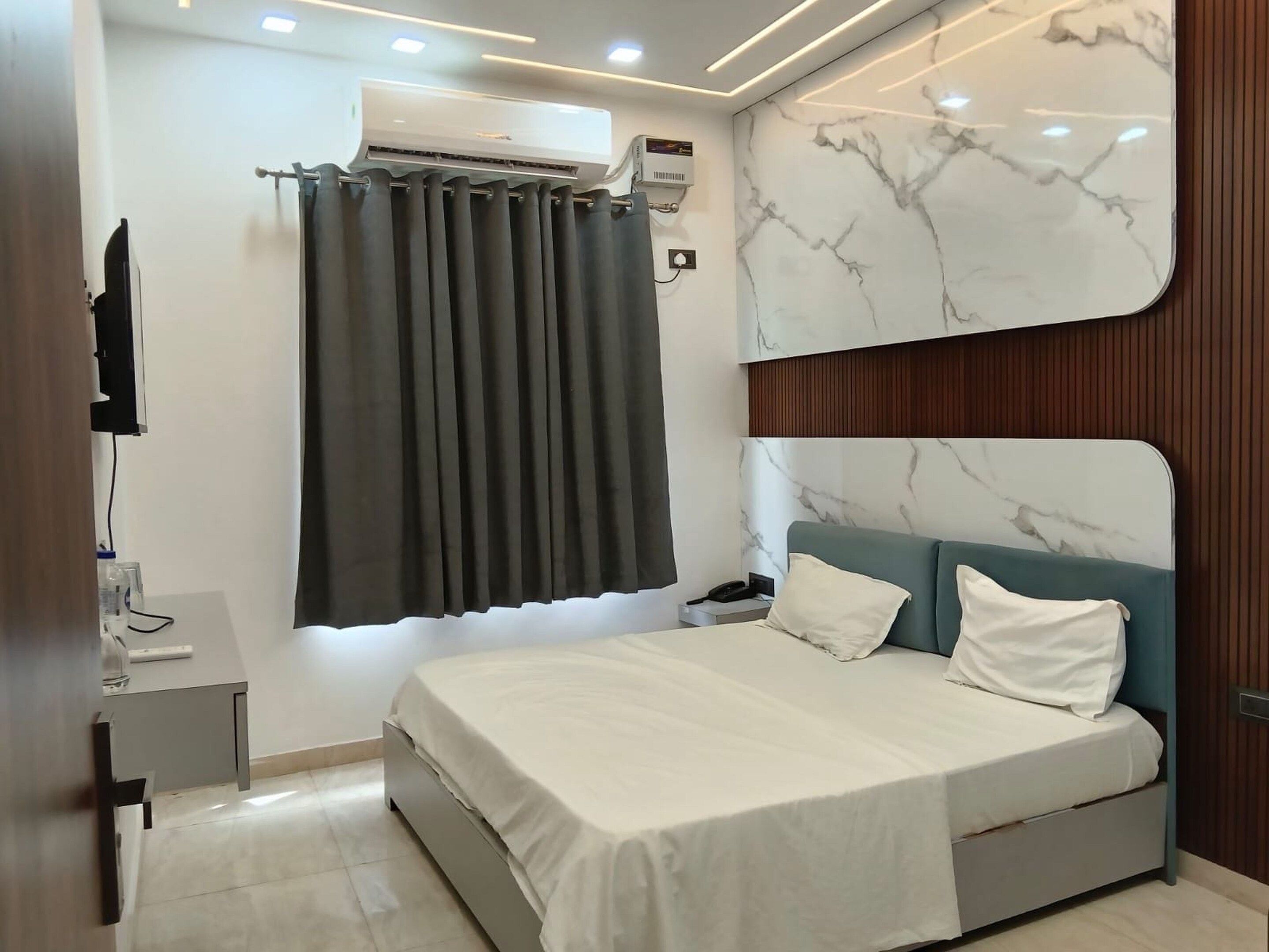 A modern bedroom with a bed, a nightstand, an air conditioning unit, and a wall-mounted TV.