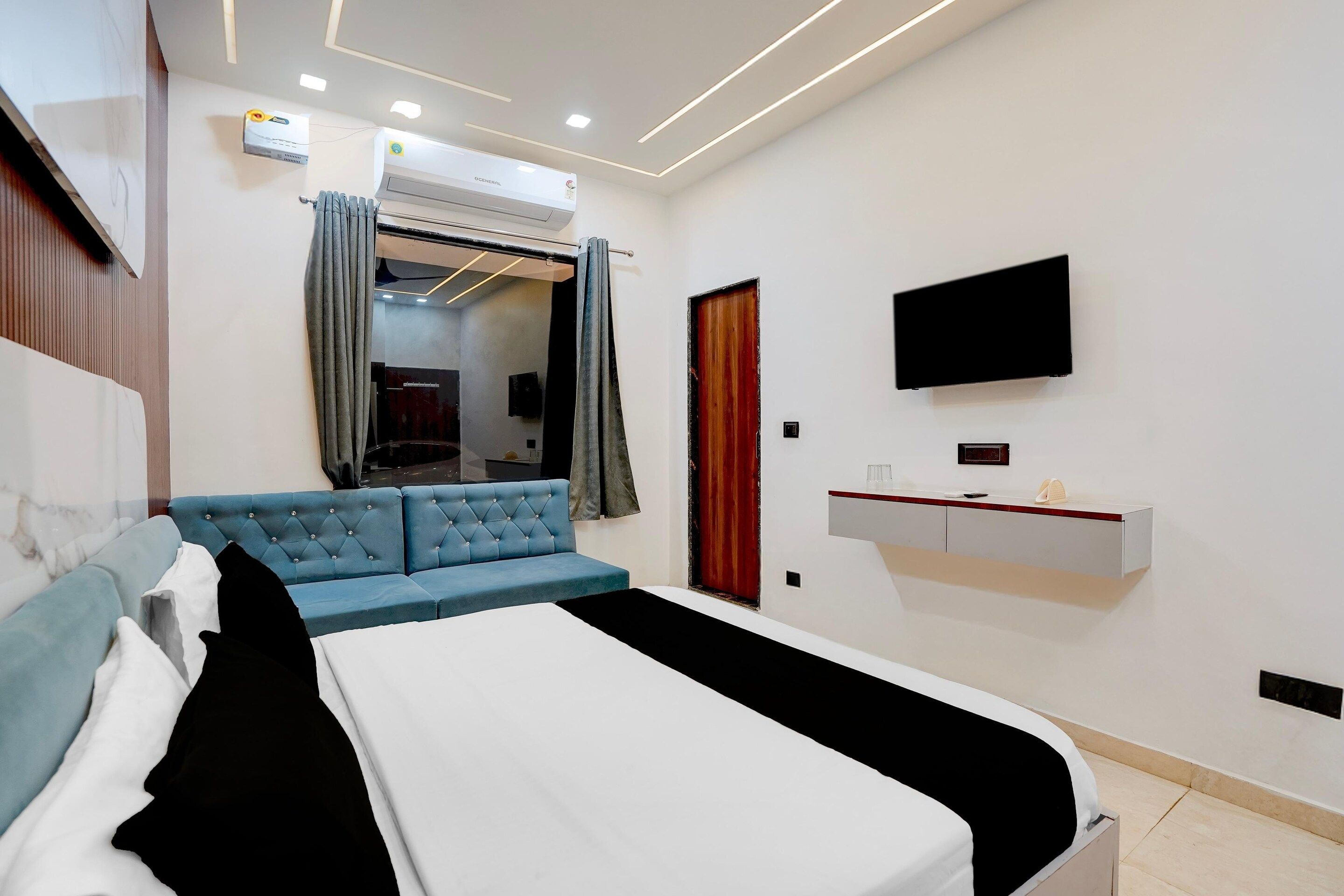 A hotel room with a bed, a blue sofa, a TV, and a small desk.