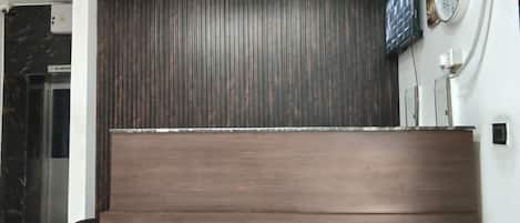 A reception desk with a dark wood finish, a clock, and a 'No Smoking' sign on the wall.