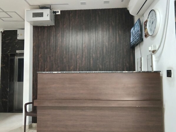 A reception desk with a dark wood finish, a clock, and a 'No Smoking' sign on the wall.