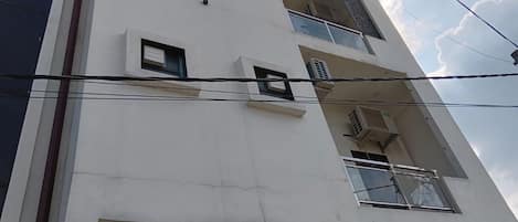A multi-story building with balconies and air conditioning units.