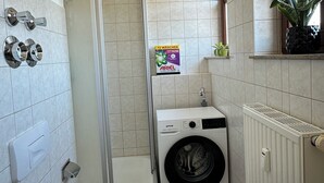 A compact bathroom with a toilet, a washing machine, and a shower enclosure. - Maisonette-Wohnung am Markt  zentral in Wolkenstein, für 4 Gäste (Wolkenstein)