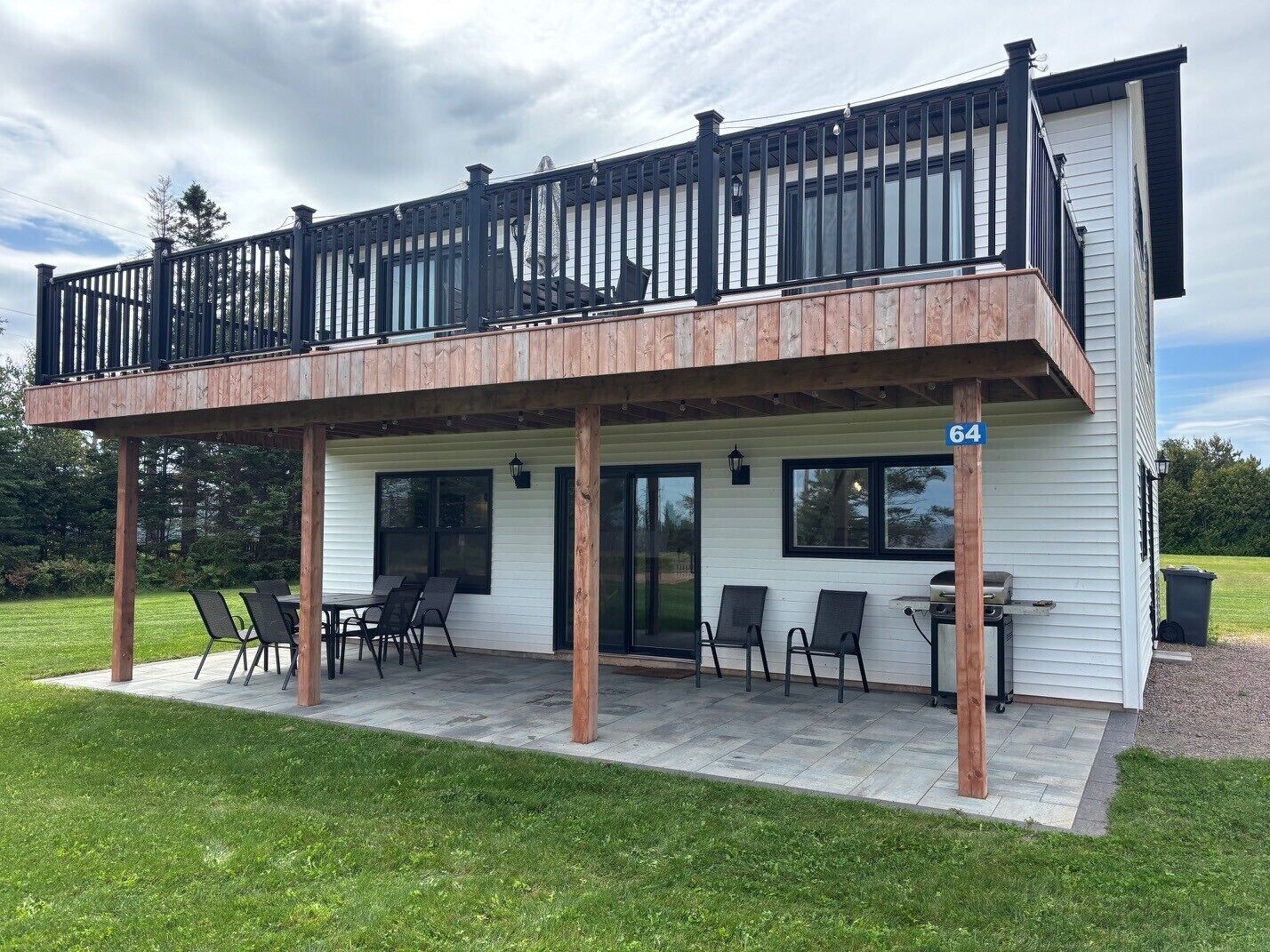 A two-story house with a balcony, a patio with outdoor seating, and a number '64' sign.