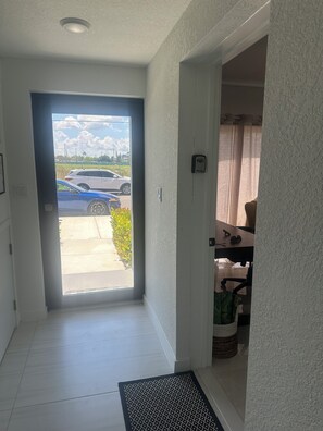 Un couloir menant à une porte donnant sur un parking et un véhicule.