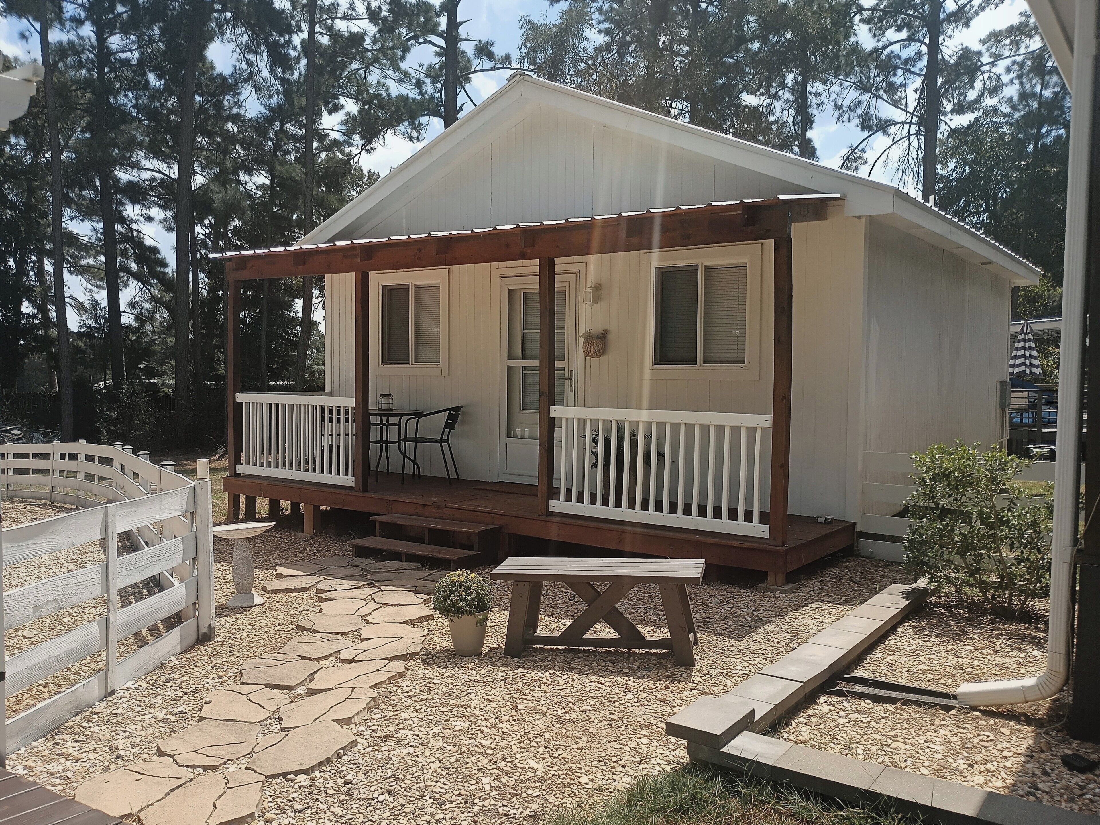 A small, single-story cabin with a porch, a table, and a bench.