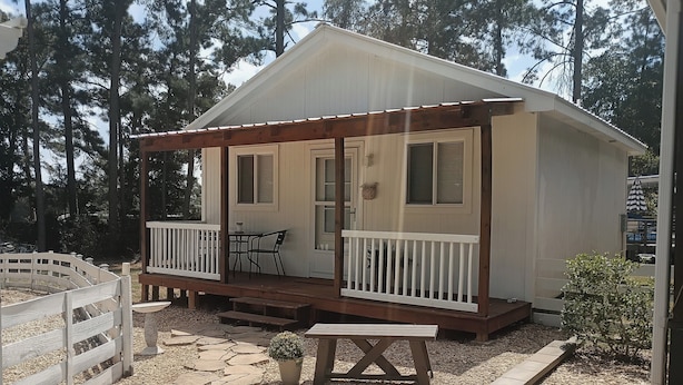 A small, single-story cabin with a porch, a table, and a bench. - Tranquil 1-bedroom cottage in the pines in Mount Enterprise (Mount Enterprise)